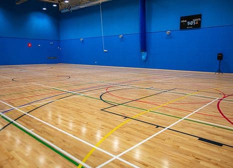 Indoor sports hall basketball court with wooden floor and blue walls